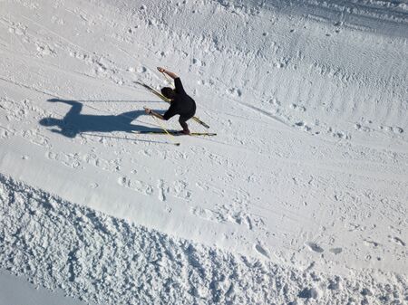 Cross-country skiing: young man cross-country skiing on a winter day (motion blurred image) - aerial imageの写真素材