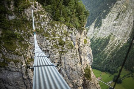 Pretty, female climber on a via ferrata - climbing on a rock in Swiss Alpsの写真素材