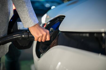 Young woman charging an electric vehicle. Car sharing concept.の写真素材