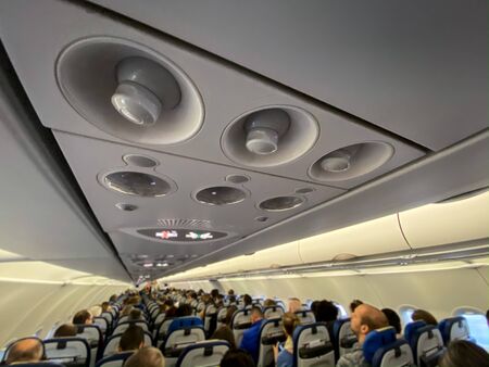 Cabin of a modern airplane filled with passangers to its full capacity during flight, after delayed...