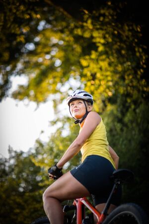 Pretty, young woman biking on a mountain bike enjoying healthy active lifestyle outdoors in summer (shallow DOF)の写真素材