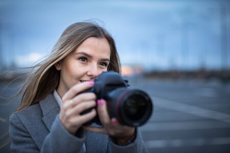 Pretty, young woman taking photos with her professional dslr cameraの写真素材