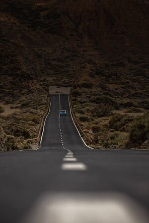 Long road in a mountain valley with a car on it - Teide National Park, Tenerife, Canary islandsの写真素材