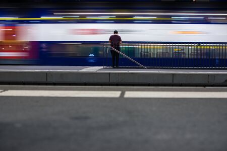 People in a trainstation with motion blurred trains moving fast (color toned image)の写真素材