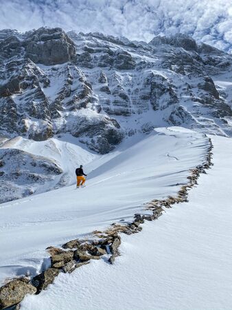 Winter sports - young man walking with snowshoes uphill in high mountains covered with lots of snow