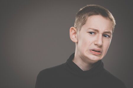 Grief-stricken little boy - feeling intense sorrow, remorse, sadnesss - studio portrait - vivid emotions seriesの写真素材