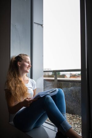 Cute female university/high school student with books in libraryの写真素材