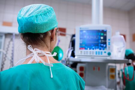 Female anesthesiologist with vital functions monitor in surgery room (color toned image; shallow DOF)の写真素材