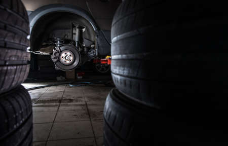 Inside a garage - modern car waiting for the mechanic to change its wheels/tires (shallow DOF; color toned image)の写真素材