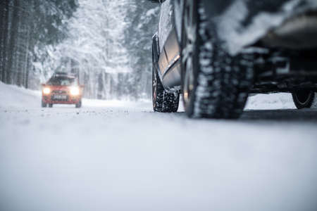 Car on a snowy winter road amid forests - using its four wheel drive capacities to get through the snowの写真素材