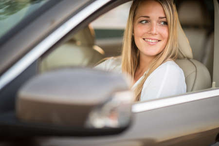 Pretty, young woman  driving a car -Invitation to travel. Car rental or vacation.の写真素材