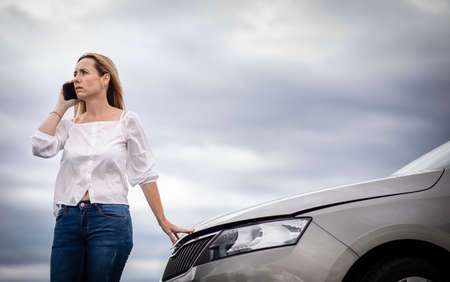 Pretty middle aged woman having car troubles - broken down car on the side of the road, calling the...