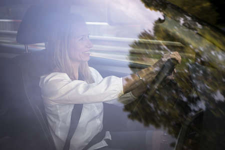 Pretty middle aged woman at the steering wheel of her car