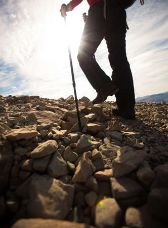 Pretty, young female hiker going uphill, crossing a snow fieldの写真素材