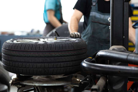 Car mechanic changind tires of a car in a repair shop/car garage (shallow DOF/color toned image)