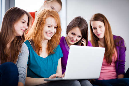 Group of female college students working on their homework/having a chat in between the lectures, using a laptop computer (color toned image)の写真素材