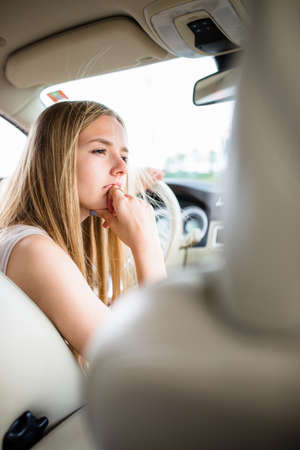 Cute female teen driver enjoying her freshly acquired driving license at the wheel of her first carの写真素材