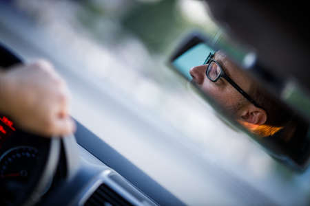 Handsome young driver driving hic car fast yet safely on the roadの写真素材