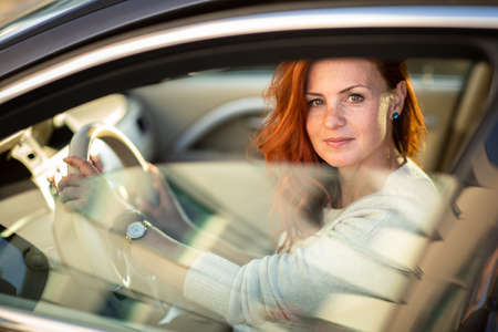 Pretty, young woman  driving a car -Invitation to travel. Car rental or vacation.の写真素材