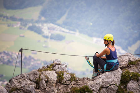 Pretty, female climber on a via ferrata - climbing on a rock in Swiss Alpsの写真素材
