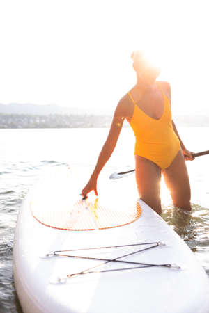 SUP Stand up paddle board concept - Pretty, young woman paddle boarding on a lovely lake in warm...
