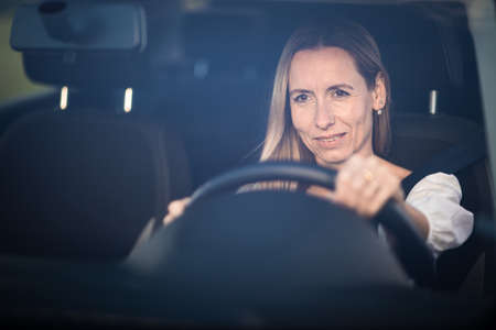 Pretty middle aged woman at the steering wheel of her carの写真素材
