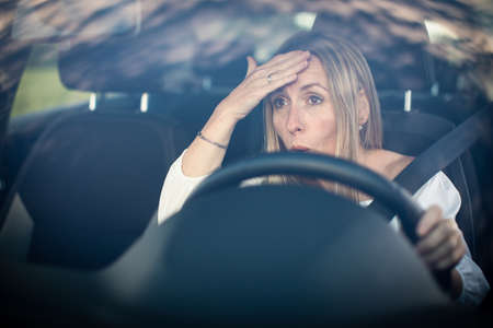 Pretty middle aged woman at the steering wheel of her car