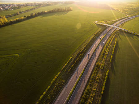 Aerial view of a highway amid fields with cars on it
