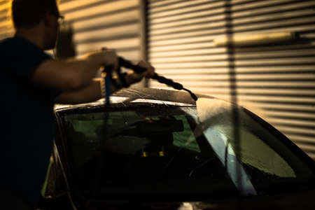 Young man washing his beloved car carefully in a manual car wash to prevent any damage and detail it properlyの写真素材