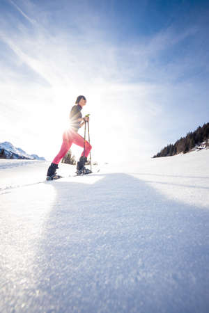 Young woman snowshoeing in high mountains, enjoying a lovely dayの写真素材