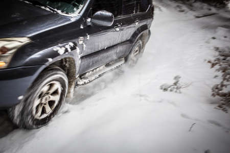 Motion blurred image of a big suv car going fast on a snow covered forest roadの写真素材