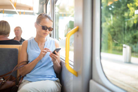 Young woman on a city tram, heading for the office early, before the rush hour beginsの写真素材