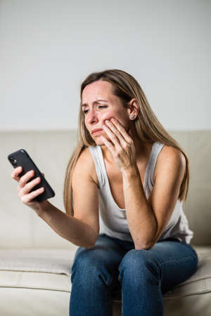 Mid-aged woman touching her cheek/mouth with painful expression because of toothache/dental issueの写真素材