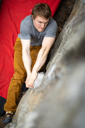 A rock climber climbing on a boulder rock outdoors. Group of friends involved in sports outside.の写真素材