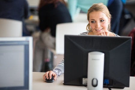 Pretty, female student looking at a desktop computer screen, learning unpleasant news about her exam results. University/office/school conceptの写真素材
