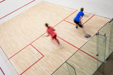 Squash players in action on a squash court (motion blurred image; color toned image)の写真素材