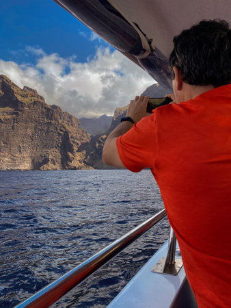 Man traveling on a boat taking pictures with his phoneの写真素材