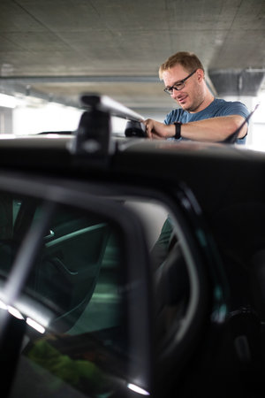 Handsome young driver getting ready to go biking - putting a bike rack on the roof of his carの写真素材