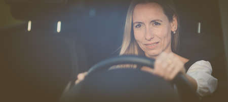 Pretty middle aged woman at the steering wheel of her carの写真素材