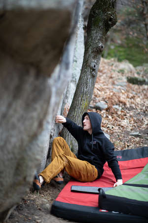 A rock climber climbing on a boulder rock outdoors. Group of friends involved in sports outside.の写真素材