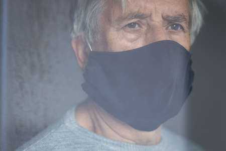Senior man wearing  a facemask during virus and flu outbreak. Virus and illness protection, home quarantine.の写真素材
