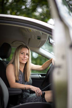 Pretty midle aged woman at the steering wheel of her car commuting to workの写真素材