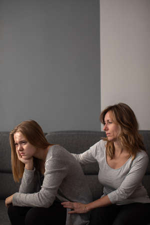 Depressed teen suffering from anxiety being taken care of by her caring motherの写真素材