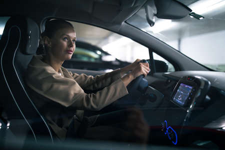 Underground parking/garage (shallow DOF; color toned image) - young woman driving her car in the underground parkingの写真素材