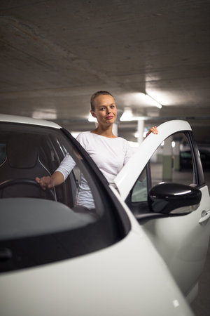 Underground parking/garage (shallow DOF; color toned image) - young woman with her car in the underground parkingの写真素材