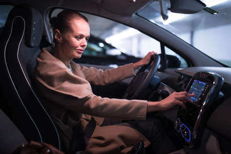 Underground parking/garage (shallow DOF; color toned image) - young woman driving her car in the underground parkingの写真素材