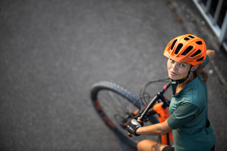 Pretty, young woman with her mountain bike going for a ride past the city limits, getting the daily cardio doseの写真素材
