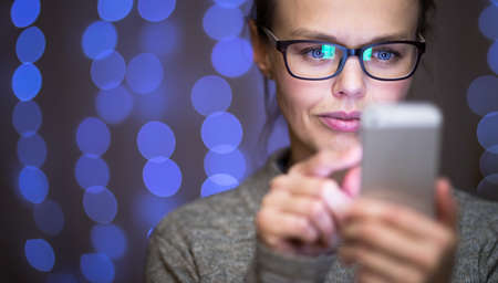 Young woman using her cell phone at homeの写真素材