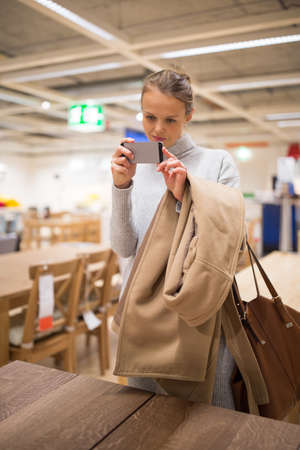 Pretty, young woman choosing the right furniture for her apartment in a modern home furnishings store (color toned image; shallow DOF)の写真素材