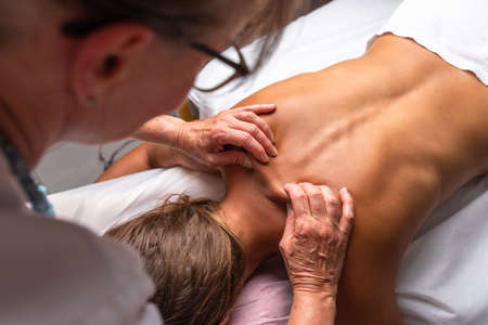 Massage procedure - neck and whole body massage by a female masseuse. doing massaging using oil. neck and whole body massage, relaxing massage, strong hands of a masseur, massage to increase work efficiencyの写真素材